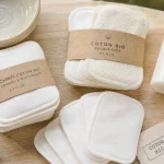 Cotons réutilisables et cotons bébé bio, sur table avec eau tiède et lotion